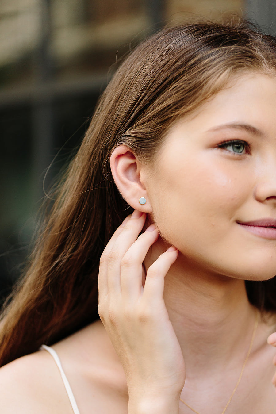 A smiling female model wearing 925 silver earring studs 