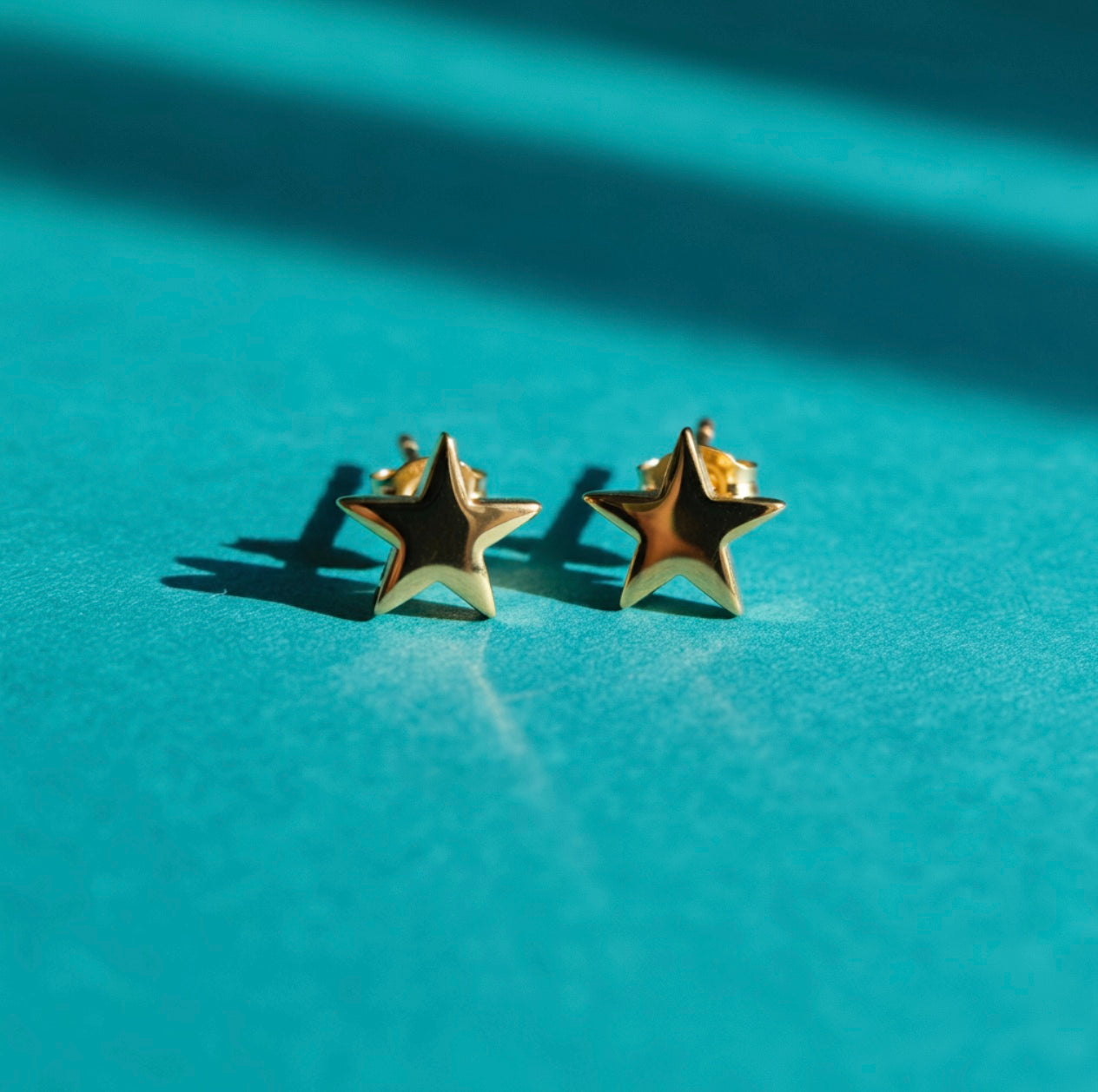 Sterling silver rocket ship earring studs with turquoise stone as the rocket ship window displayed against a navy blue paper background with gentle lighting