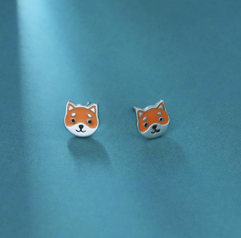 orange colored enamel sterling silver earring studs of cute shiba inu faces with a turquoise paper background