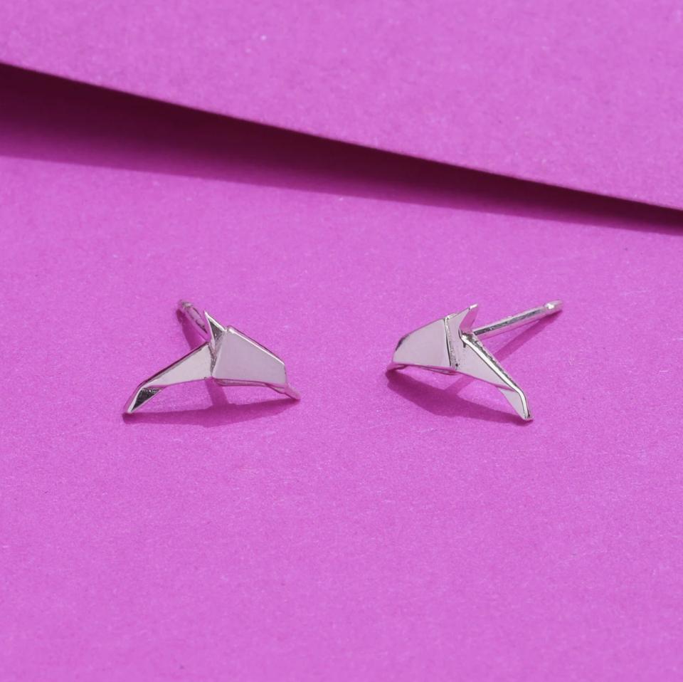 origami style dolphin earrings studs in sterling silver displayed against bright magenta pink paper
