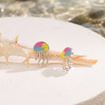 Jellyfish-shaped earrings with colorful designs on a shell.