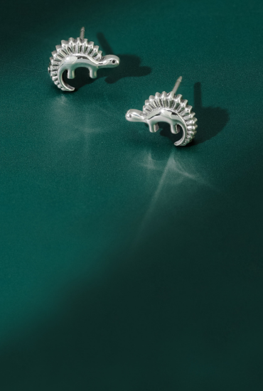 Pair of silver animal-shaped earrings on a green background